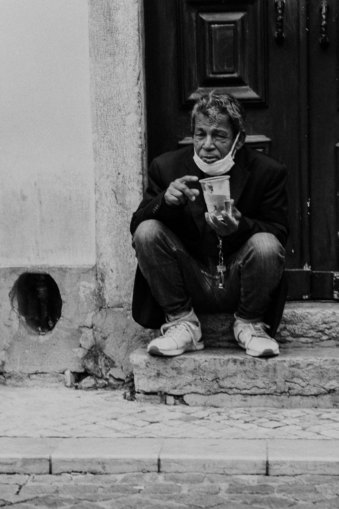 uomo seduto davanti alla porta a Lisbona