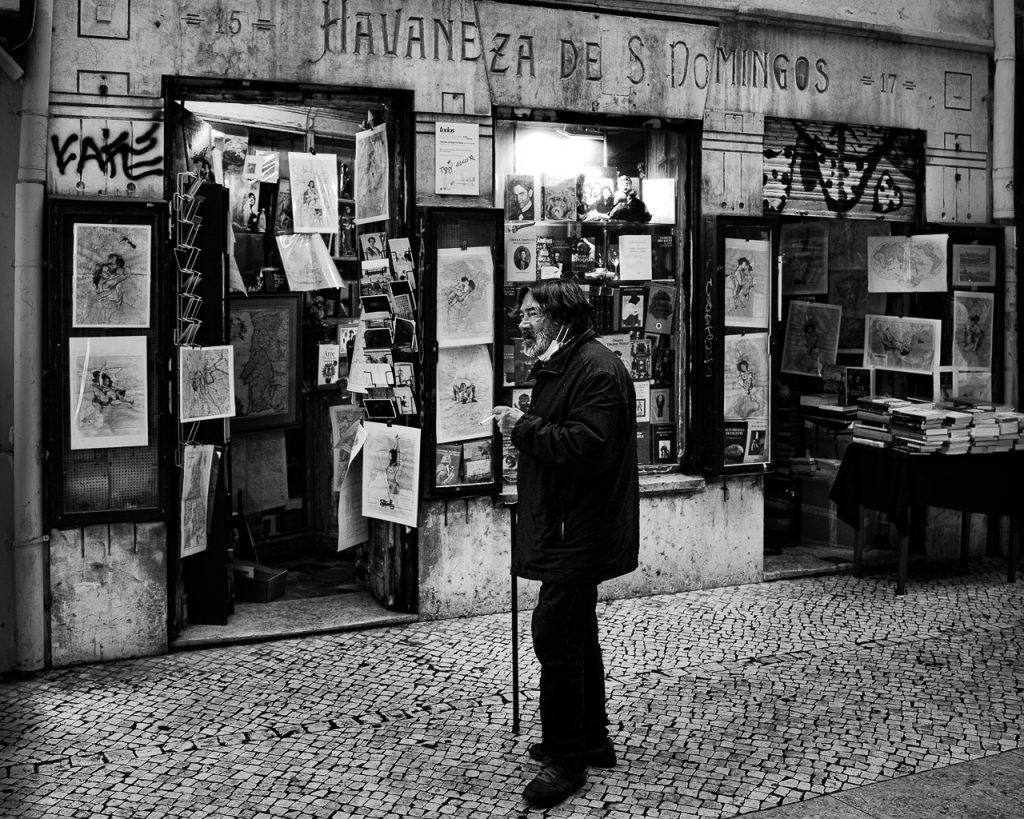 uomo che passeggia davanti libreria a Lisbona
